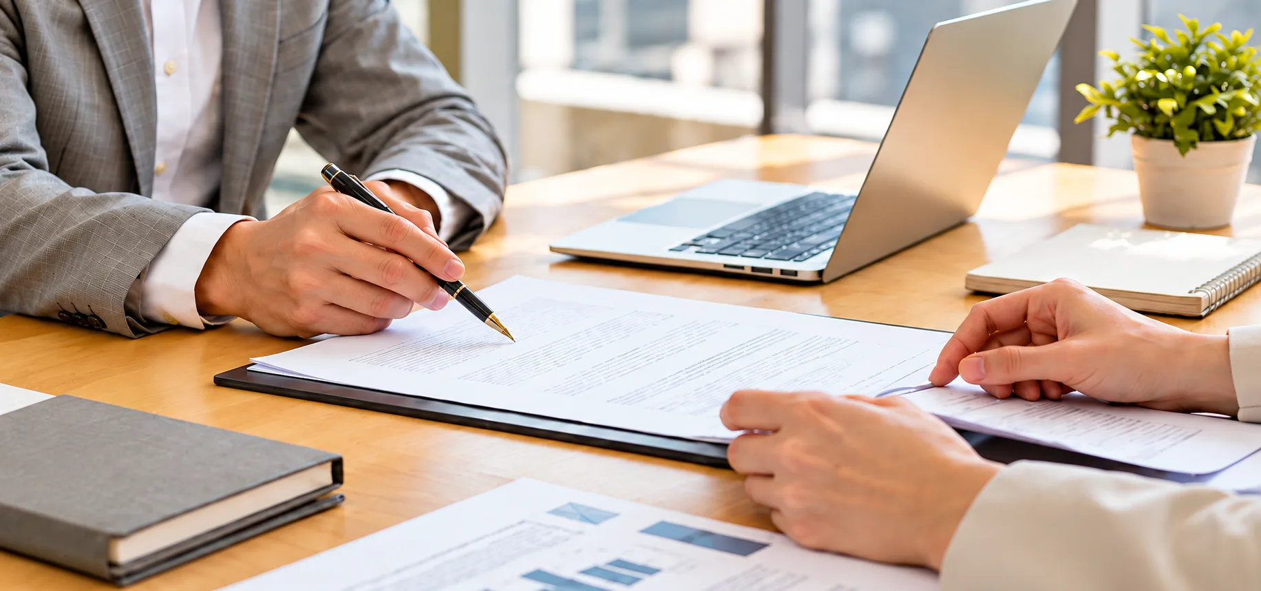 Two professionals reviewing a policy document at a desk with a laptop